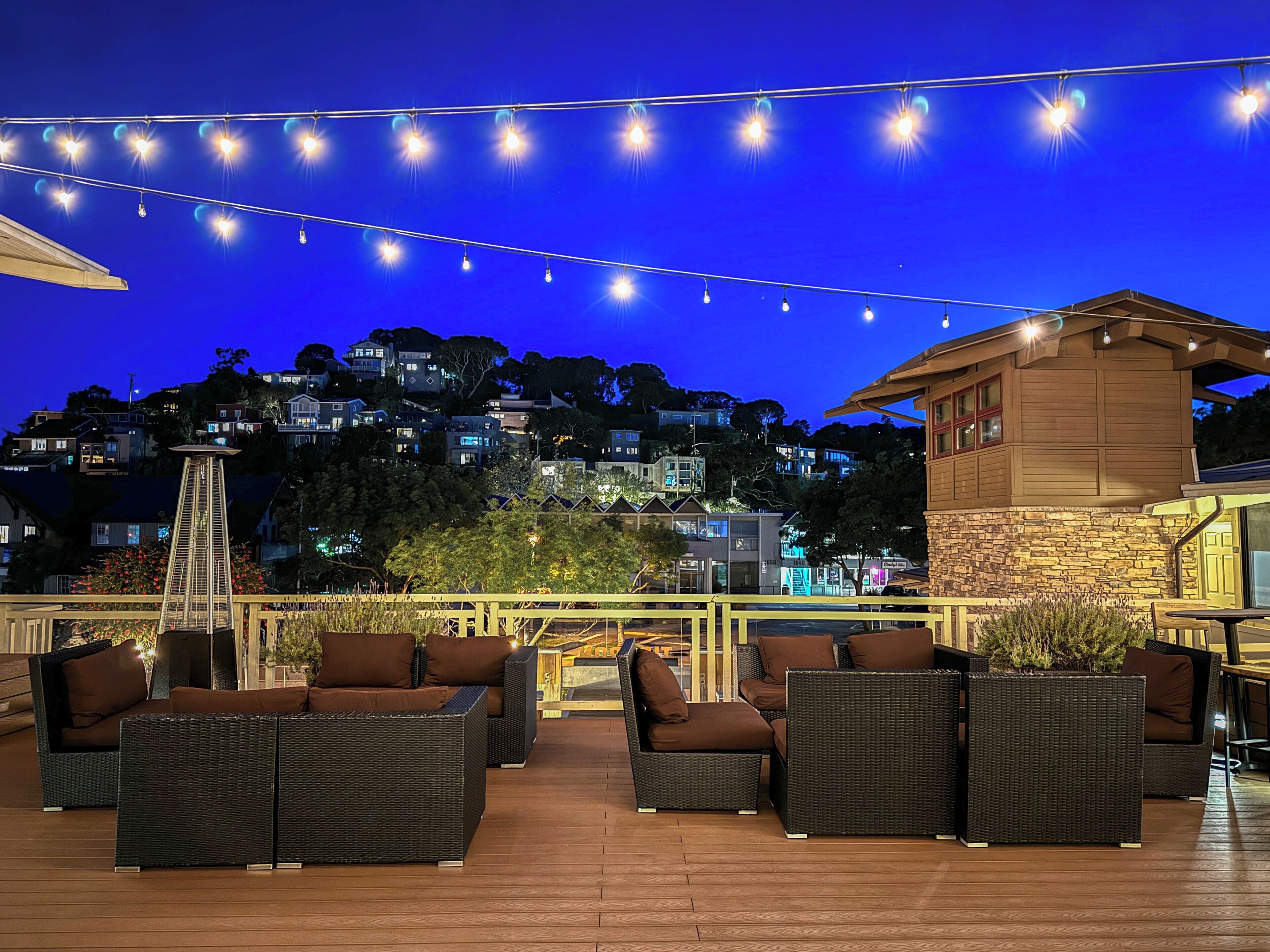An outdoor patio with wicker furniture and string lights against a night sky.