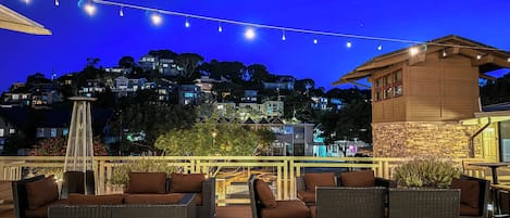 An outdoor patio with wicker furniture and string lights against a night sky.