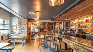A bar area with a stone wall, wooden bar counter, and multiple stools.