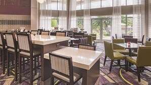 A spacious dining area with multiple tables and chairs, large windows, and a view of the outdoors. - La Quinta Inn & Suites by Wyndham Fort Worth North (Fort Worth)