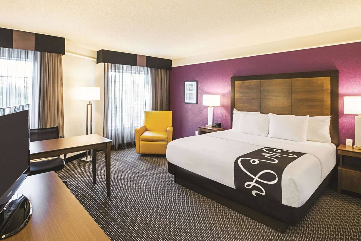 A hotel room with a bed, a desk, a chair, and a TV.