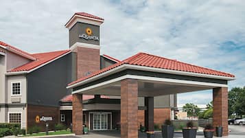 A La Quinta hotel with a covered entrance, brick facade, and red-tiled roof.