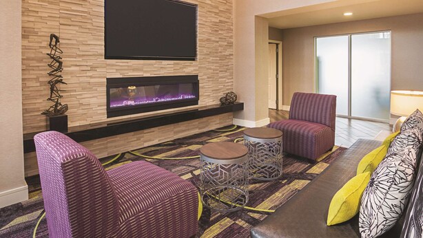 A modern living room with a fireplace, comfortable seating, and a flat-screen TV mounted on the wall. - La Quinta Inn & Suites by Wyndham Fort Worth North (Fort Worth)