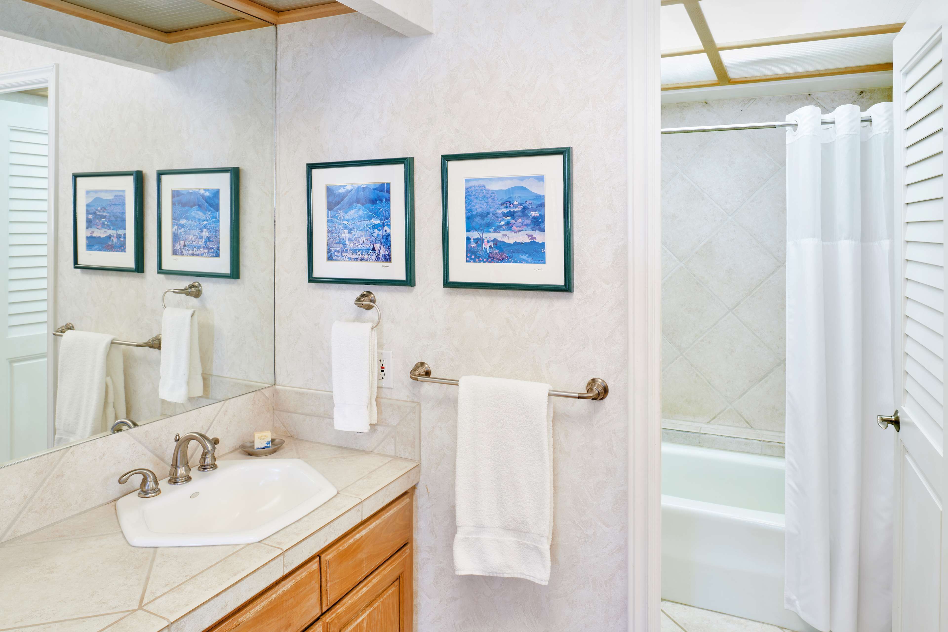Une salle de bain avec un lavabo, un miroir et trois tableaux encadrés accrochés au mur.