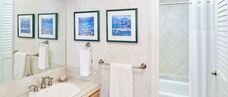 Une salle de bain avec un lavabo, un miroir et trois tableaux encadrés accrochés au mur.