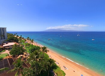 A modern outdoor seating area with a view of a bridge and a landscaped garden. at Aston at The Whaler on Kaanapali Beach