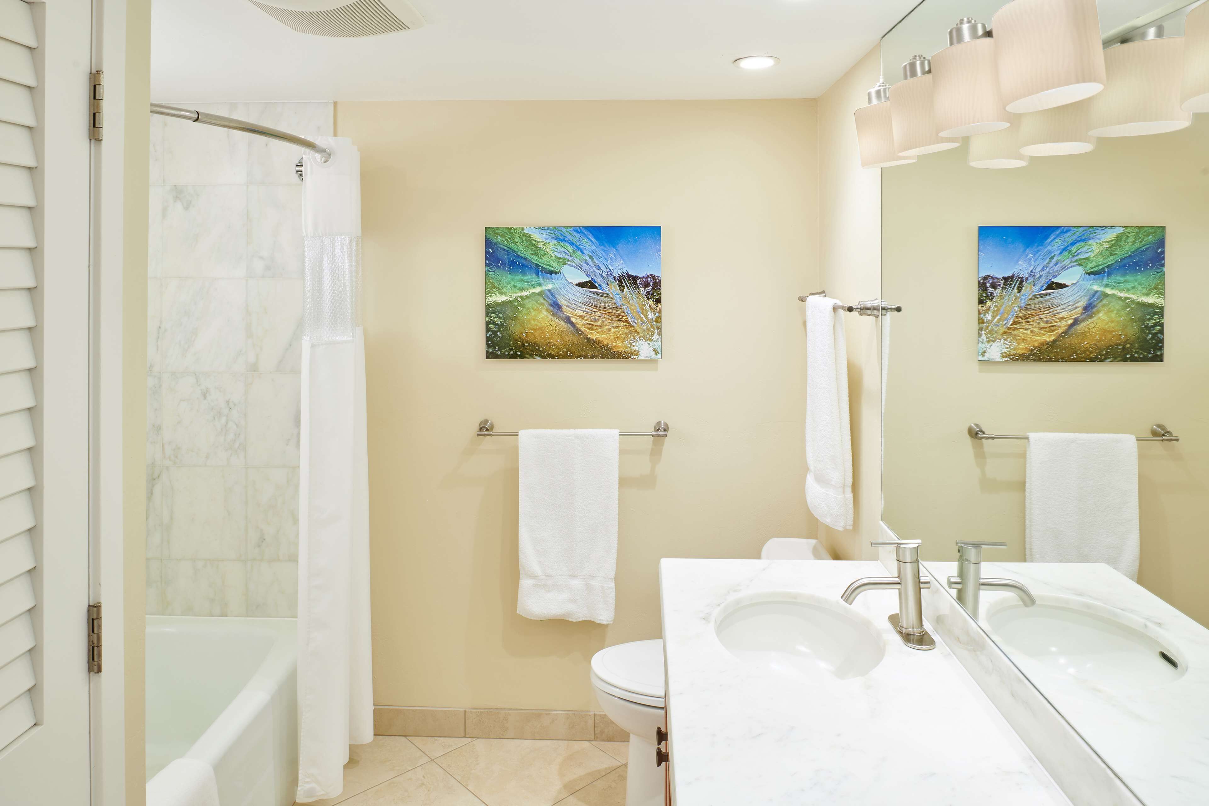 Ein modernes Badezimmer mit einer Badewanne, einer Toilette und einem Waschbecken. Zwei Handtücher hängen an Handtuchhaltern und es gibt zwei Bilder an der Wand.