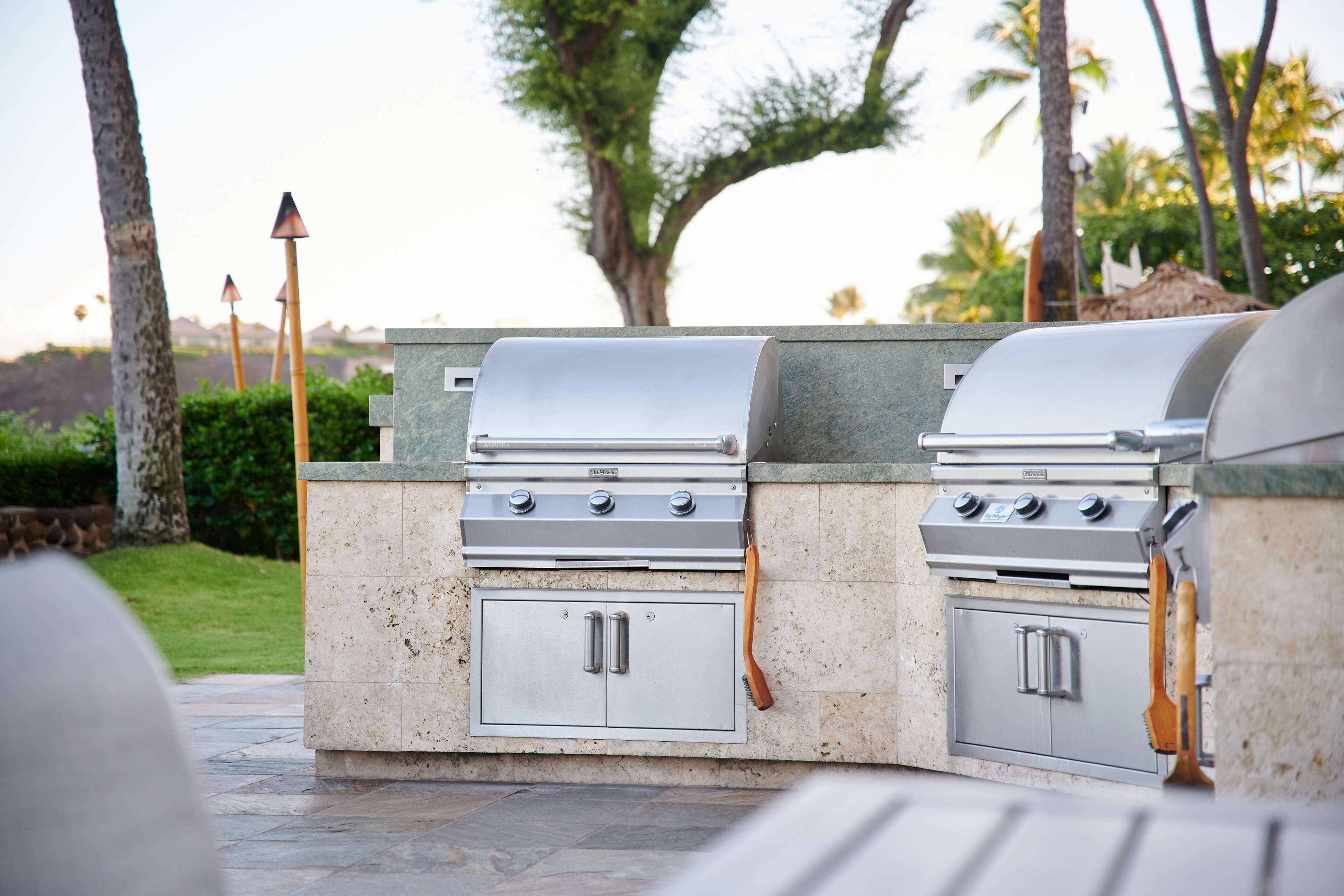 A built-in outdoor kitchen with a stainless steel range and oven, integrated into a stone countertop.