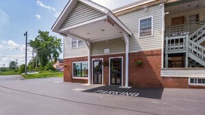 A building with a covered entrance, a brick facade, and a staircase. - Northway Inn Queensbury - Lake George (Queensbury)