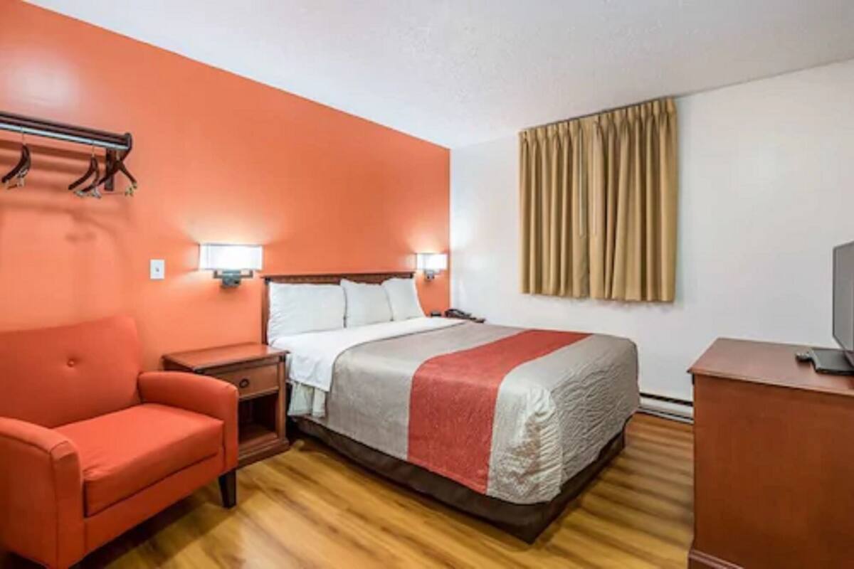 A hotel room with a bed, a chair, a desk, and a television.