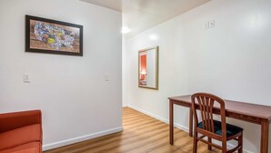 A room with a wooden floor, a dining table with a chair, and two framed artworks on the wall. - Northway Inn Queensbury - Lake George (Queensbury)