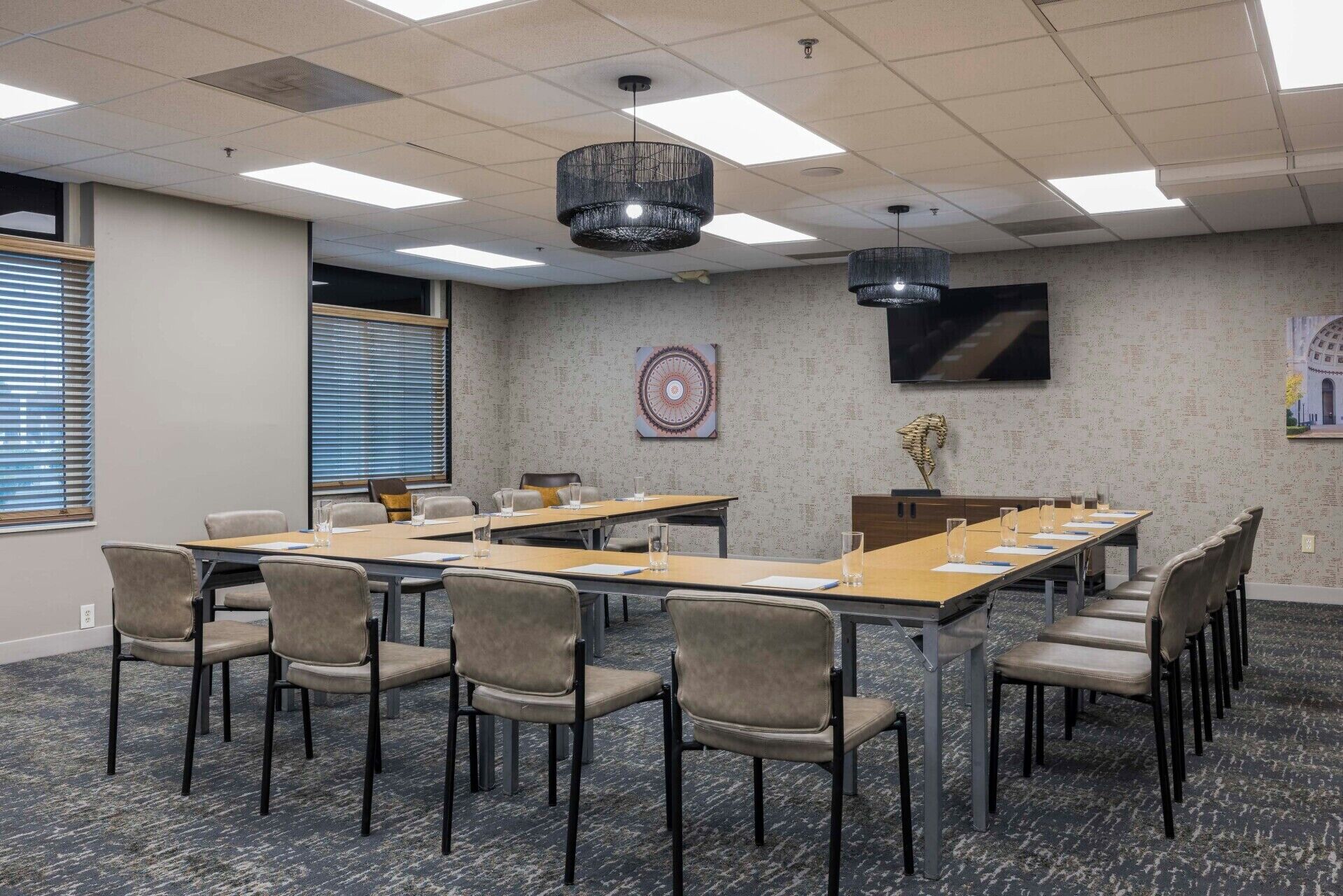 A conference room with long tables, chairs, and a large screen.