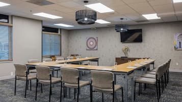 A conference room with long tables, chairs, and a large screen.