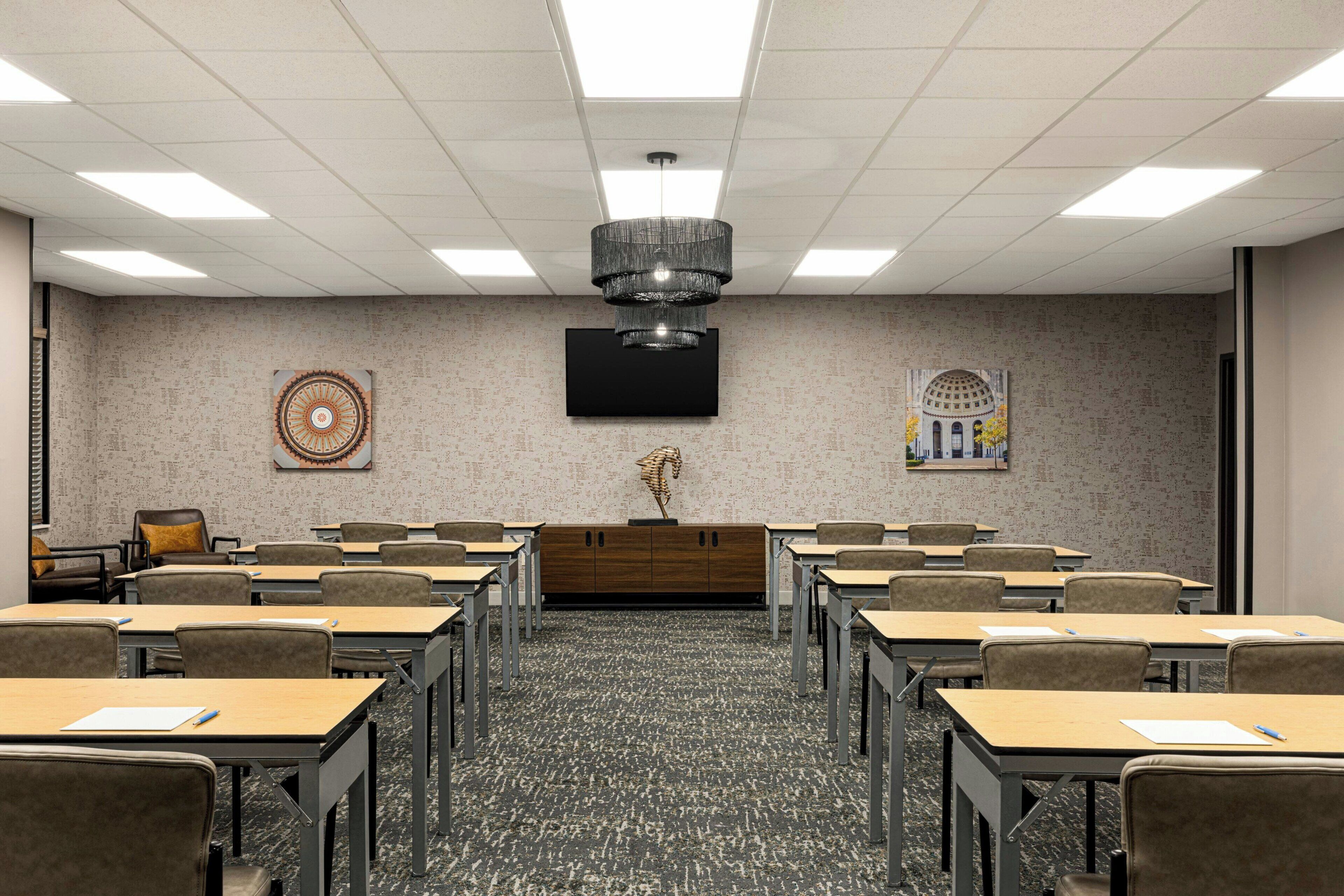 A conference room with a modern chandelier, a flat-screen TV, and a decorative wall piece.