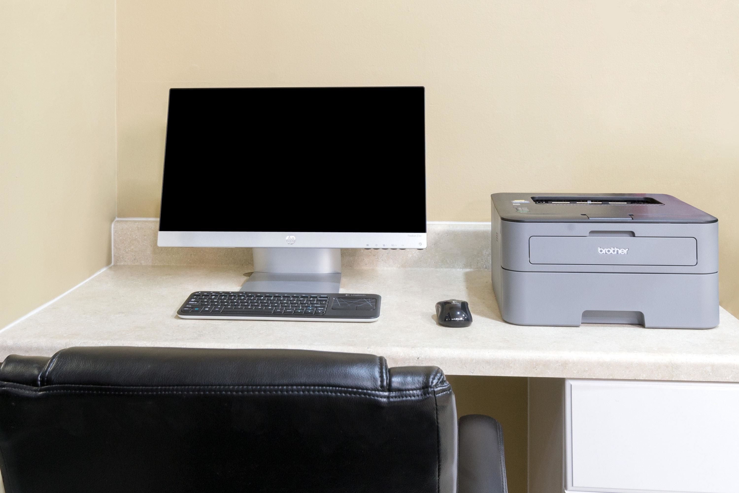A desk with a computer monitor, keyboard, mouse, and Brother printer.