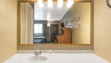 Un bagno d'hotel con un grande specchio, un lavandino bianco e un mobile bagno in legno con specchio.