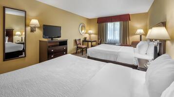 Una habitación de hotel con dos camas, televisión, escritorio y silla.