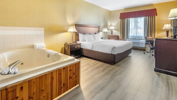 A hotel room with a large bathtub, a double bed, a desk, and a chair. - Quality Inn Greenville North (Greenville)