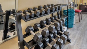 A gym with multiple rows of dumbbells on racks, a blue trash bin, and a red chair. - Quality Inn Greenville North (Greenville)