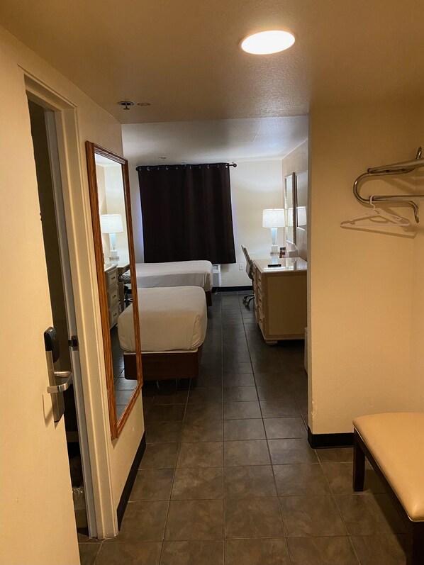 Hotelkamer met een bed, bureau met stoel, spiegel, kapstok en badkamer met toilet en wastafel.