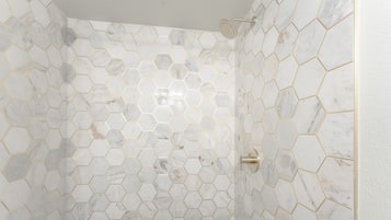 A shower with hexagonal marble tiles and a gold outline.