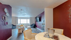 A modern living room with a round table, two armchairs, a sofa, and a TV mounted on the wall. - Hotel Jefe at Ojos Locos- No Resort Fee (North Las Vegas)