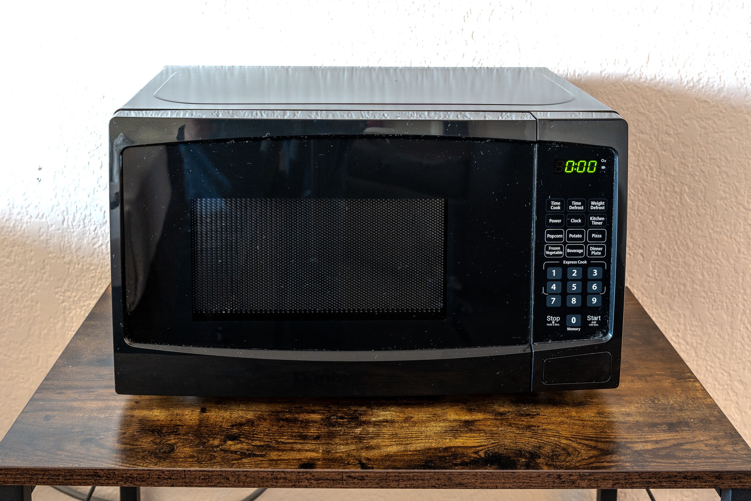 A black microwave oven on a wooden table.