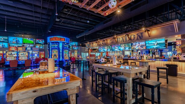 A gaming arcade with multiple screens and wooden tables. - Hotel Jefe at Ojos Locos- No Resort Fee (North Las Vegas)