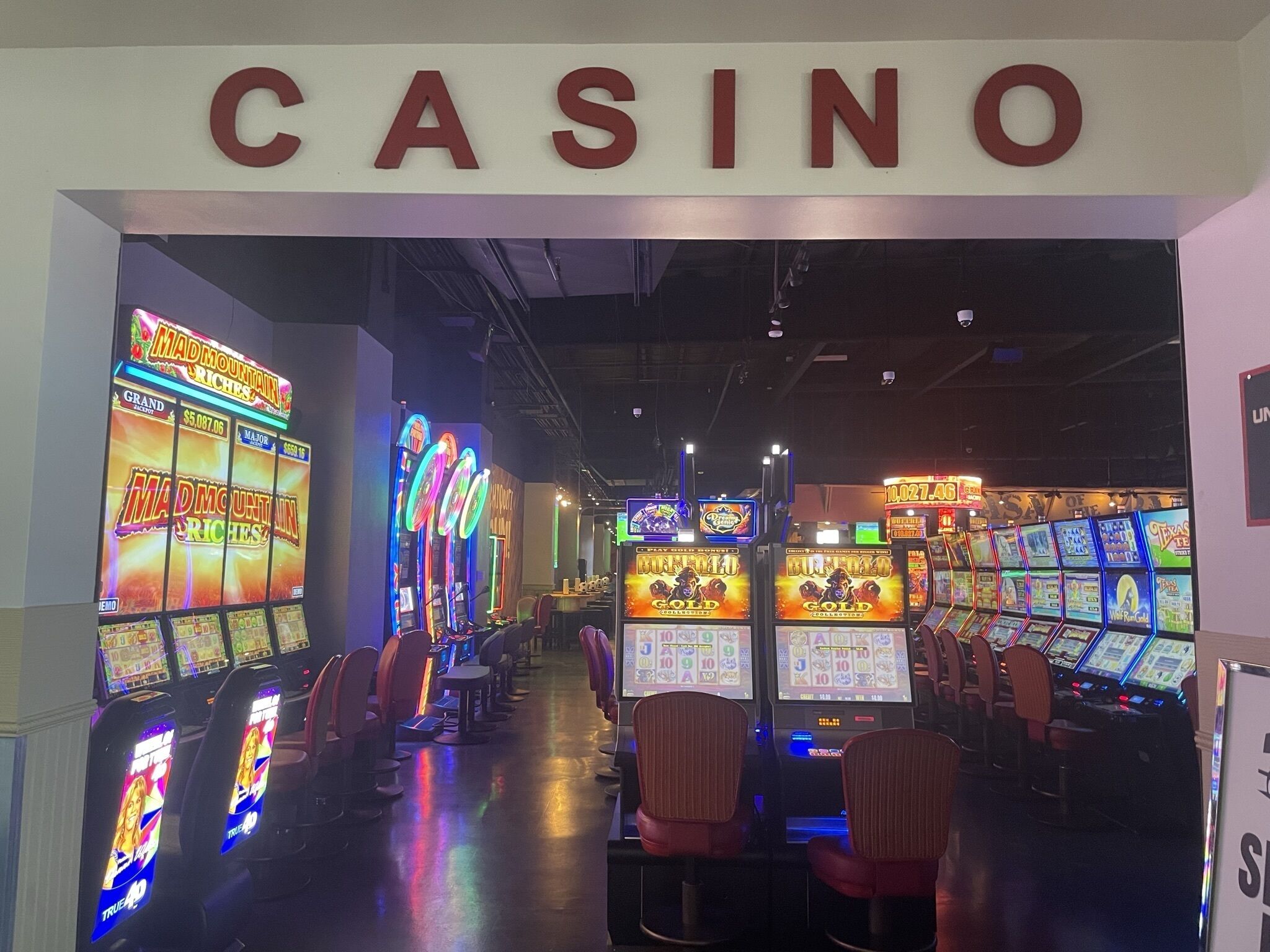 L’intérieur d’un casino, avec des machines à sous et une enseigne sur laquelle on peut lire « CASINO ».