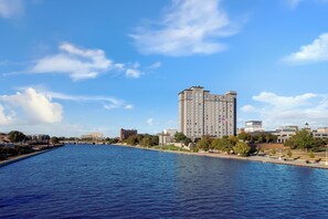 A large hotel with a view of a river and a bridge in the background.