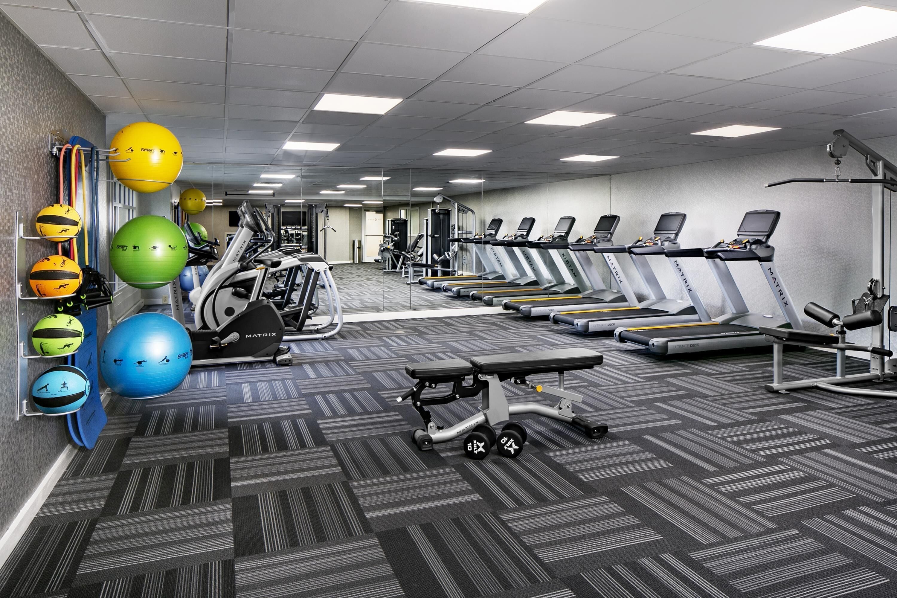 Ett gym med löpband, träningsbollar och styrketräningsmaskiner.