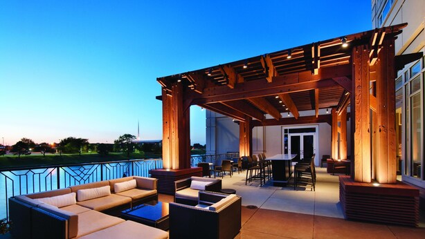 An outdoor patio with seating, a pergola, and a view of a body of water. - Hyatt Regency Wichita (Wichita)