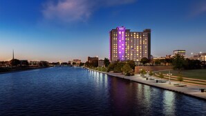 A high-rise hotel with illuminated windows and a view of a river.