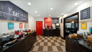 A breakfast area with a checkered floor, a red door, and various breakfast items displayed on counters. - Hampton Inn Tuscaloosa-East (Cottondale)