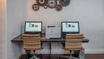 Un espace de travail équipé de deux ordinateurs, d’une imprimante et de deux chaises de bureau.