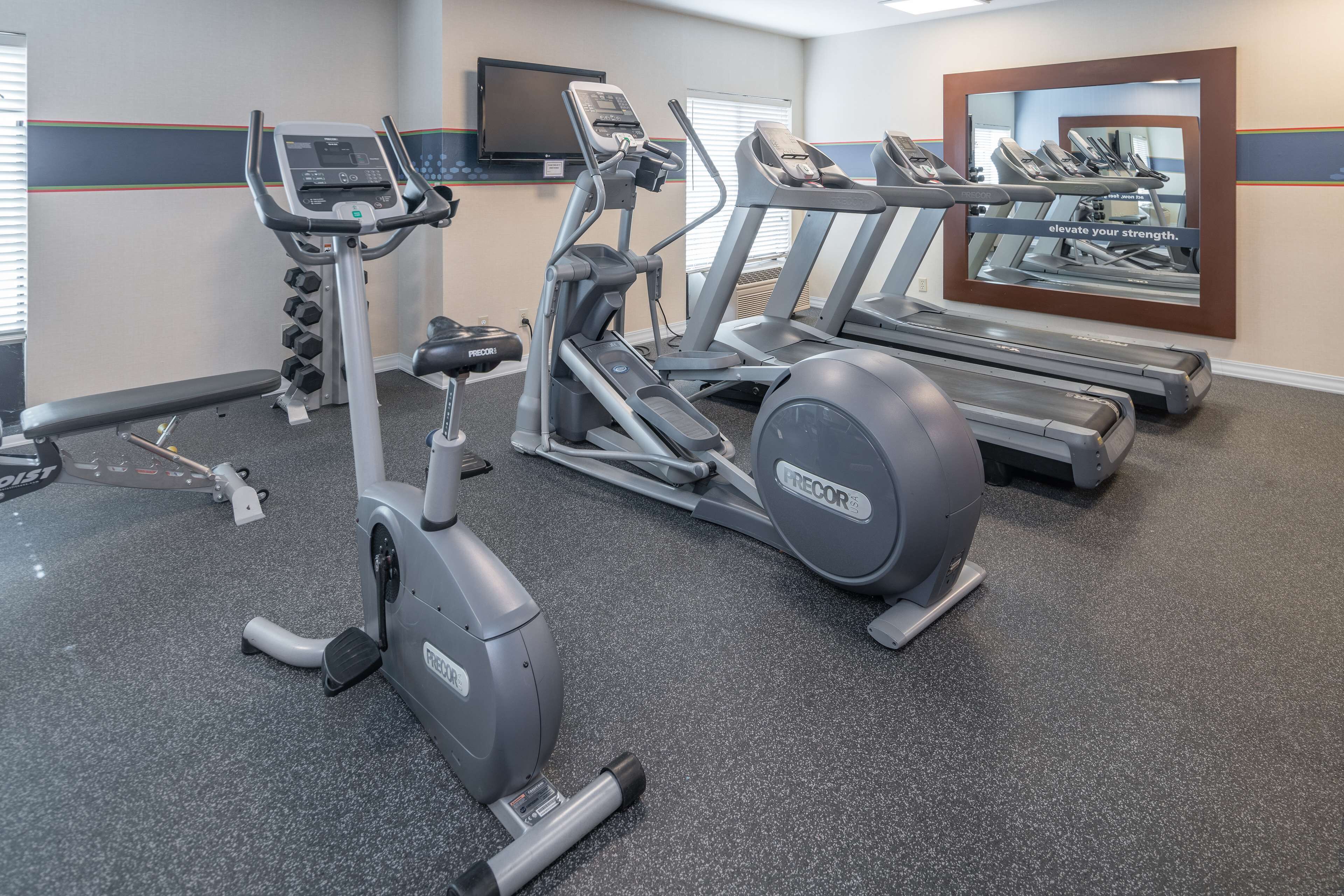 A gym with treadmills, an elliptical, and free weights.
