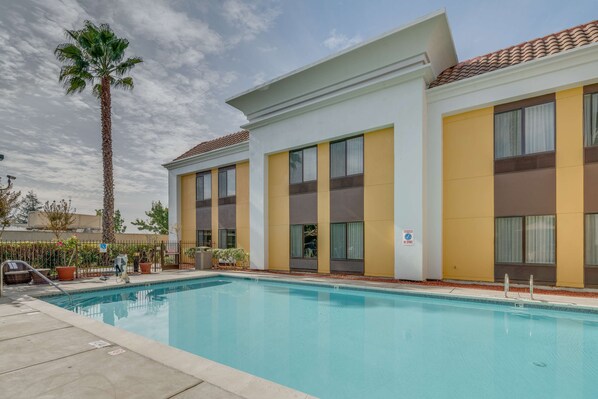 A hotel with a swimming pool, large windows, and a palm tree. - Hampton Inn Livermore (Livermore)