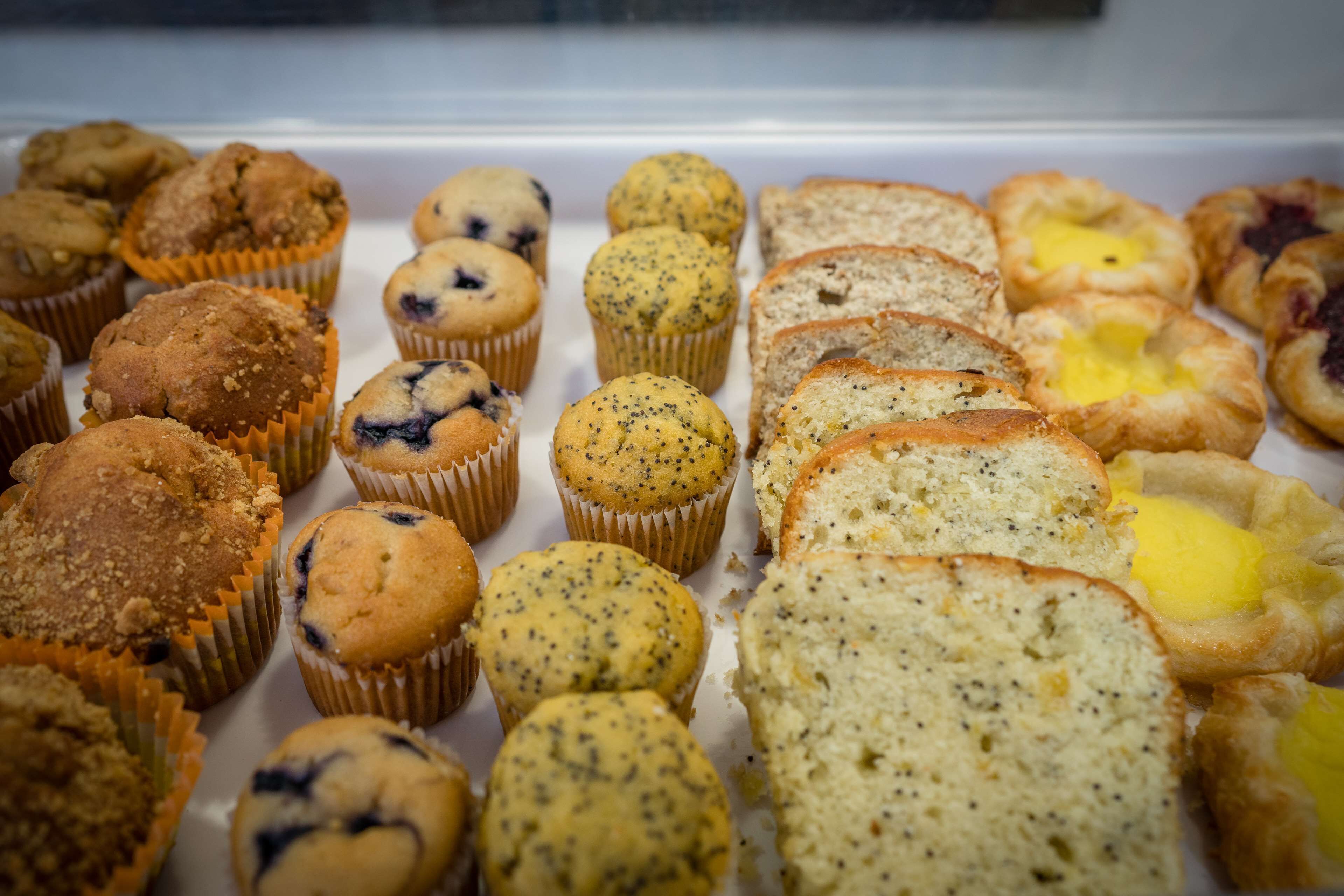 A variety of muffins and pastries displayed in a bakery case.