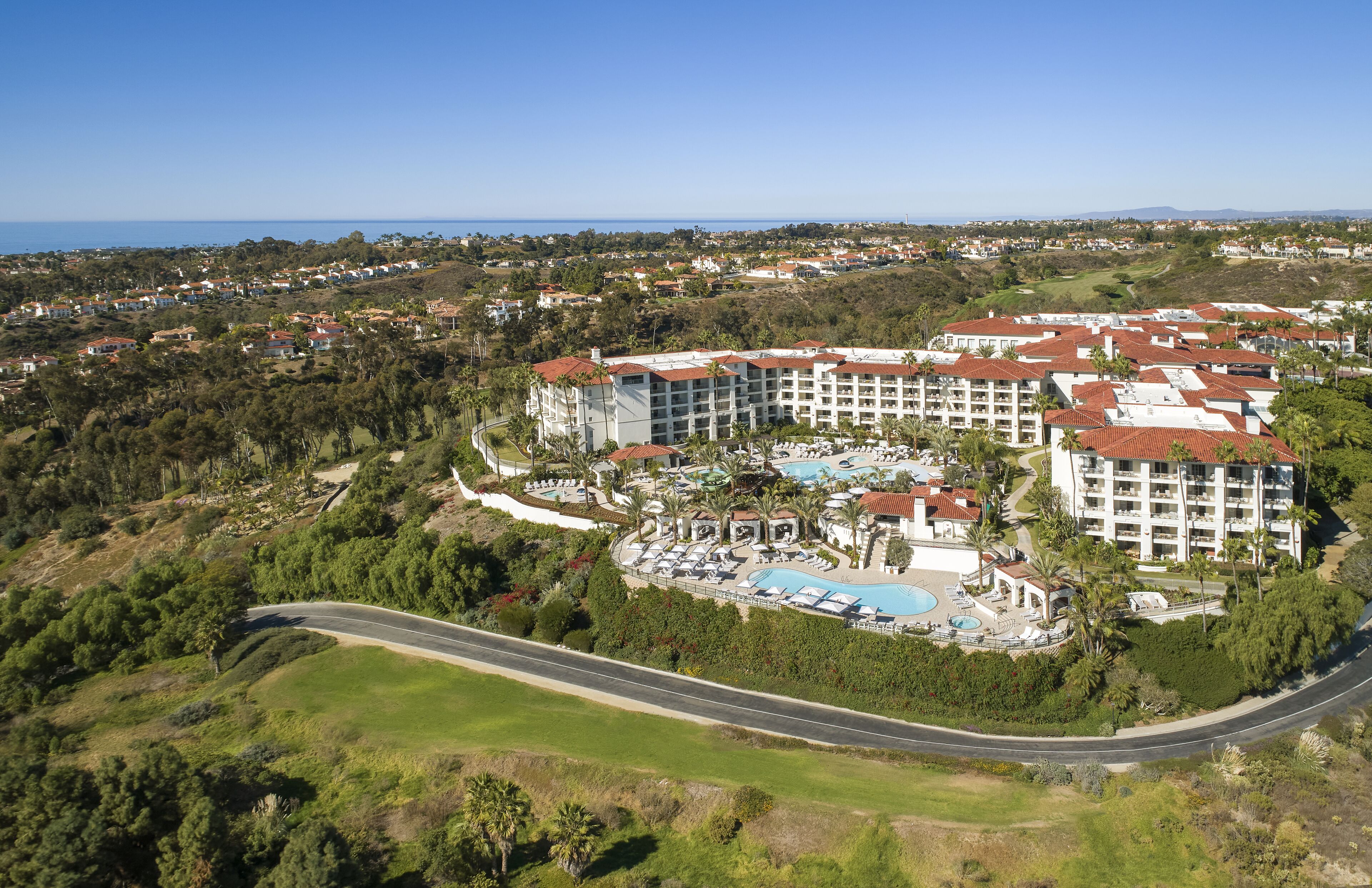 A resort with multiple buildings, a swimming pool, and a road curving through the landscape.