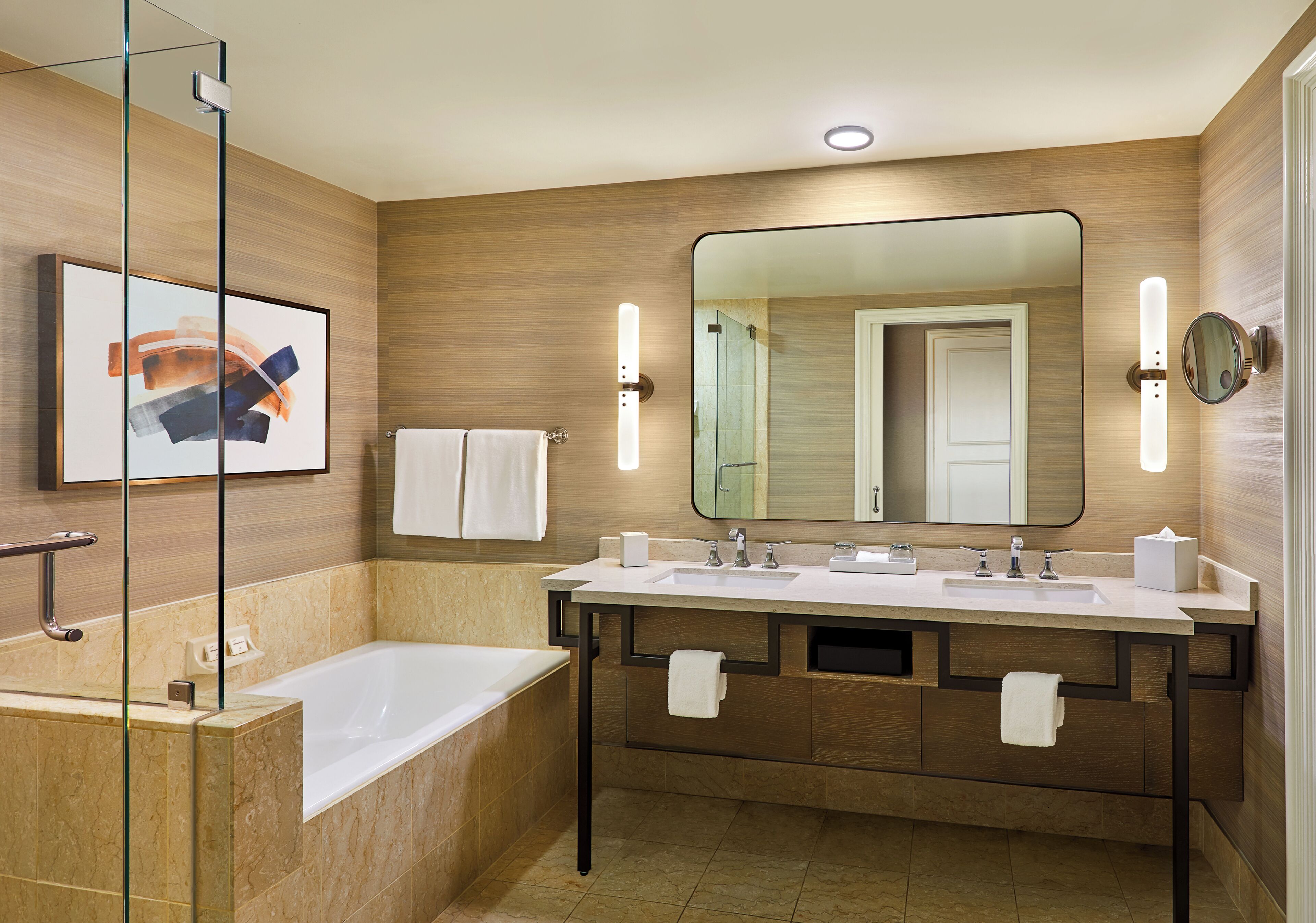A modern bathroom with a bathtub, double sinks, and a large mirror.