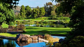 Escape to a serene golf course setting surrounded by lush greenery and a tranquil pond.