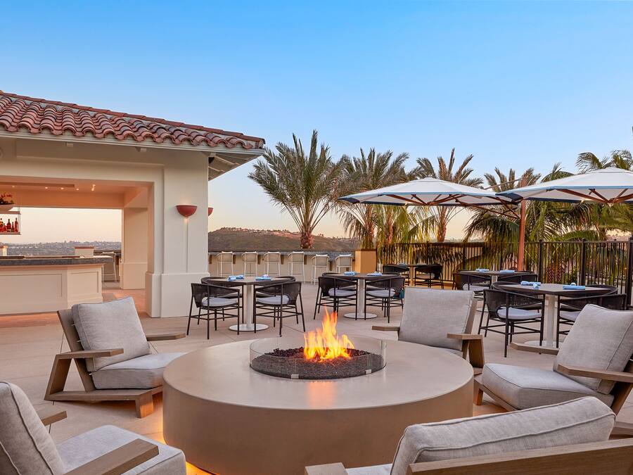 An outdoor patio with a fire pit, seating, and umbrellas.