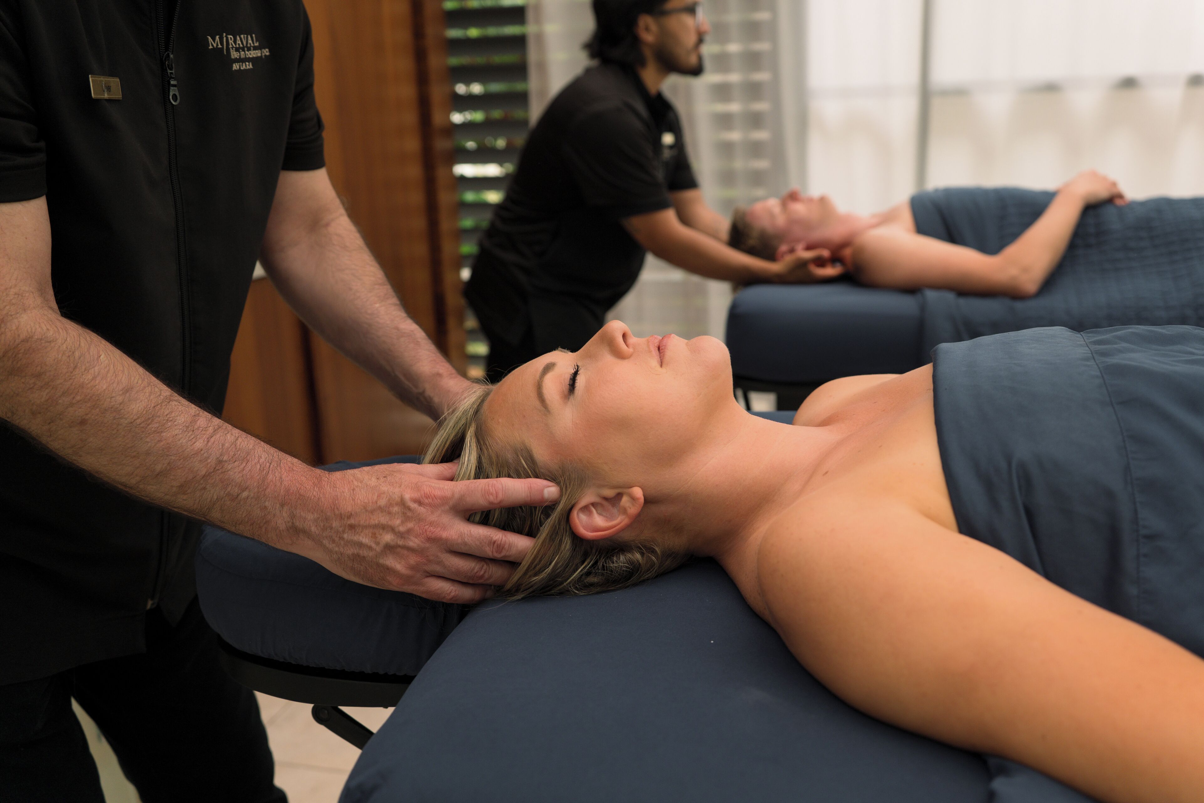 A massage therapy session in a room with a massage table and a person receiving a head massage.