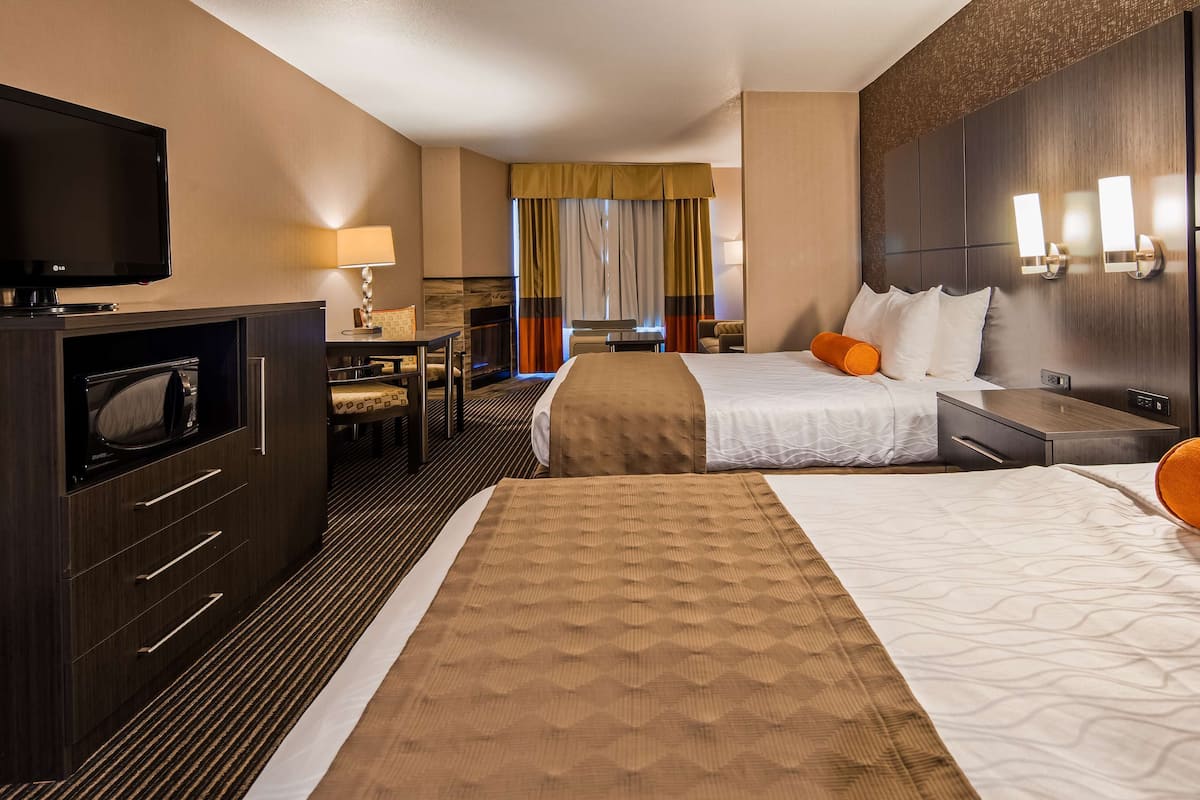 A hotel room with two beds, a desk, a TV, and a microwave.