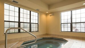 A hot tub with a metal ladder, large windows, and tiled flooring.