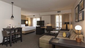 A hotel room with a bed, desk, sofa, and TV.