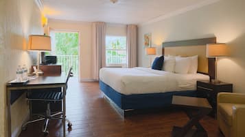 Habitación de hotel con cama, escritorio, silla y vistas a zonas verdes.