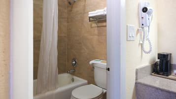 Een badkamer met een bad, toilet en een aan de muur bevestigde haardroger.