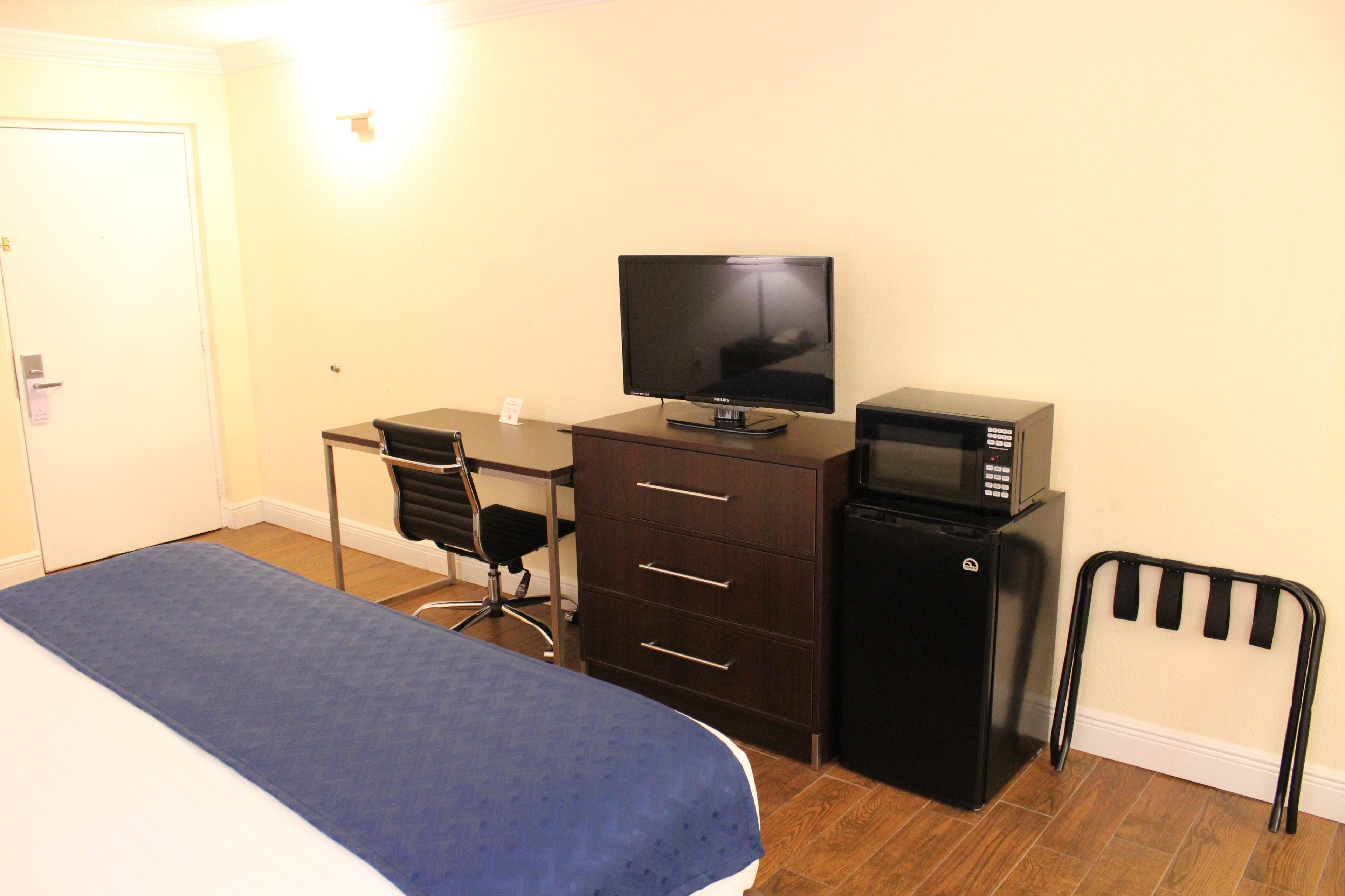 Une chambre à coucher comprenant un lit, un bureau, une télévision, un réfrigérateur et une chaise.