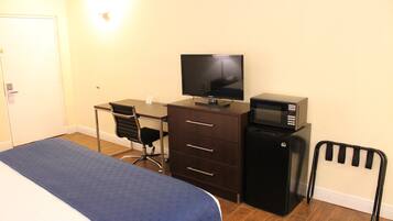 Une chambre à coucher comprenant un lit, un bureau, une télévision, un réfrigérateur et une chaise.